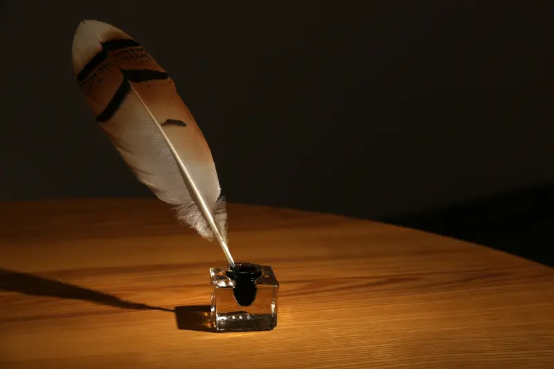 Plume d’oie posée dans un encrier sur une table en bois