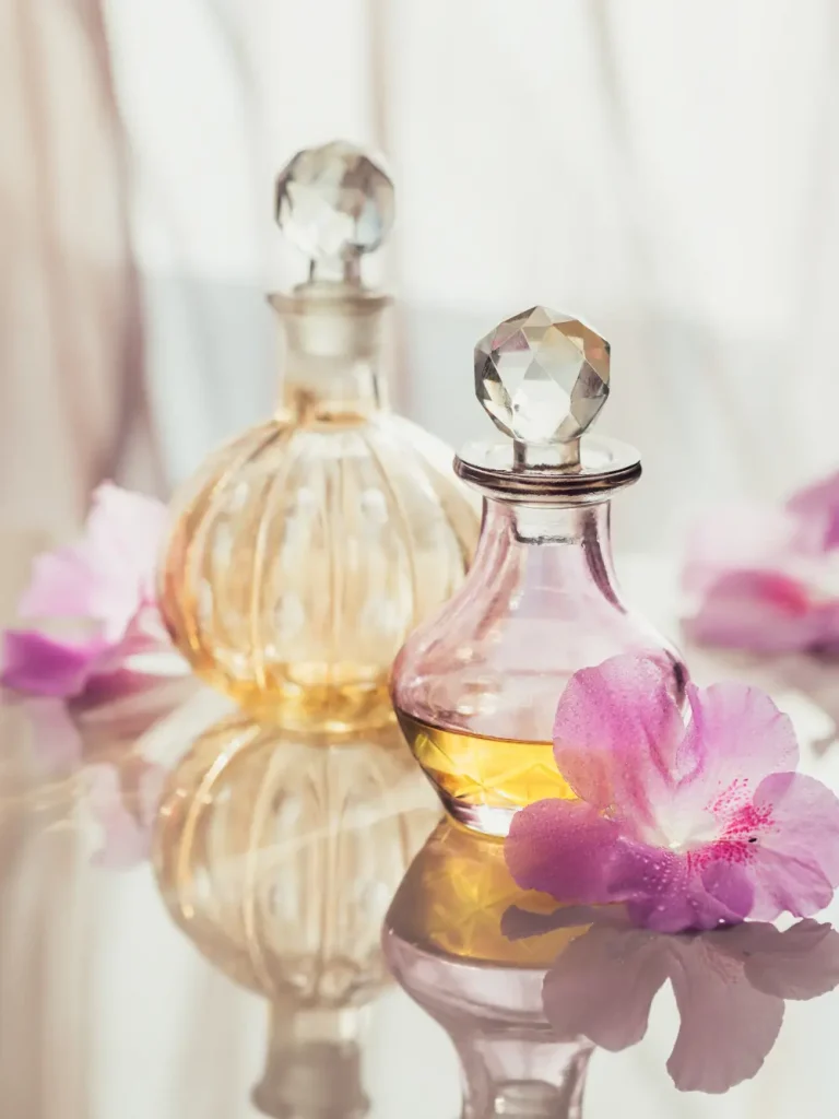 Flacons de parfum en verre entourés de fleurs roses